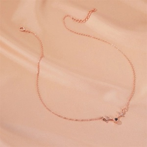 Close-up of rose gold elk antler necklace with projection stone on silk background