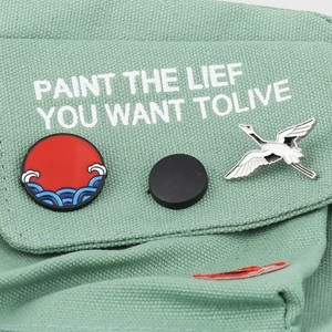Classic sun crane enamel brooches pinned on light green canvas bag with white print