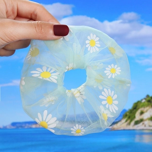 Close-up of light green mesh scrunchie with white daisy floral pattern for summer hair