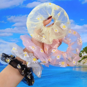 Close-up of colorful daisy print organza scrunchies in yellow, pink, white, and black