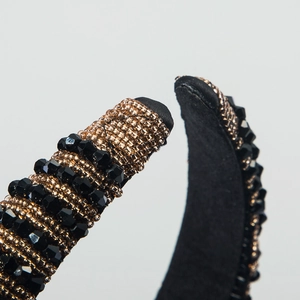 Macro view of crystal beaded headband with gold beads and black velvet edge