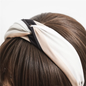 Knotted fabric headband in tricolor stripe design worn on hair over a white background