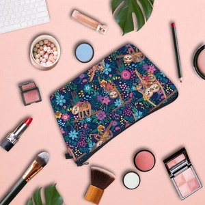 Flat lay of a sloth pattern travel makeup bag surrounded by cosmetics on pink background