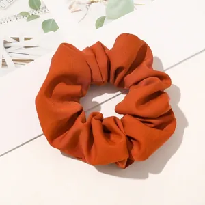 Close-up of caramel plaid fabric scrunchie with thick pleated texture and soft cotton feel