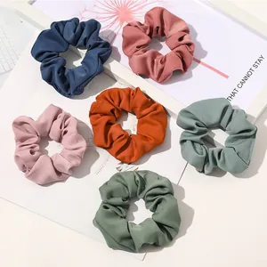 Close-up of six multicolor matte fabric scrunchies in navy blue and pastel green tones