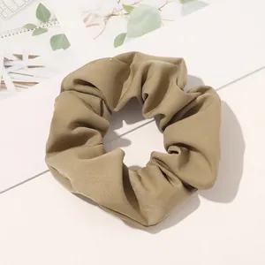 Close-up of khaki twill fabric scrunchie with rich pleated texture and subtle sheen