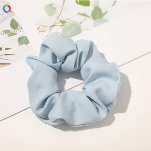 Detail shot of light blue satin scrunchie with soft pleated texture and elegant shine