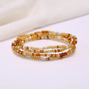 Macro shot of multi-layer colorful seed beads in gold and amber for beach waist jewelry