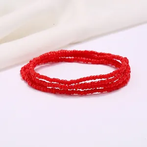 Macro detail of red multilayer seed bead waist chain on a minimalist white background