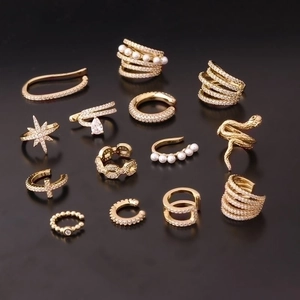 Set of 13 gold ear cuffs with cubic zirconia and pearls on black background