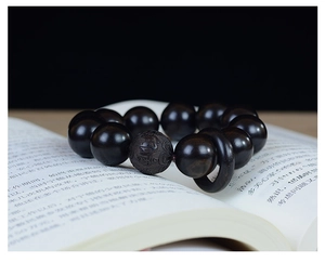 Gros plan de perles de prière en bois sombre avec une perle gravée sur un livre ouvert