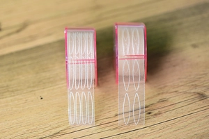 Detailed comparison of narrow and wide mesh lace eyelid tapes on a wooden surface