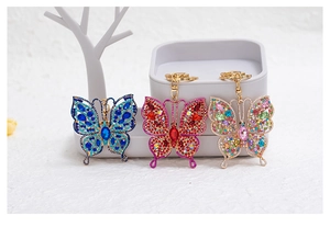 Close-up of three butterfly keychains with colorful crystals and metallic alloy finish