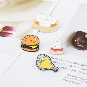 Set of four cartoon food enamel pins featuring burgers and dumplings on a magazine