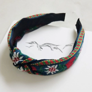 Detail of navy blue ethnic headband with floral embroidery and top knot design