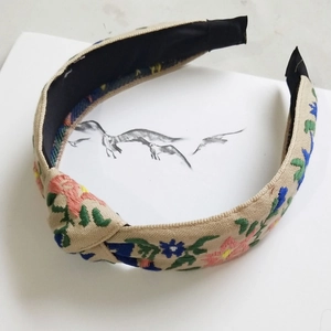 Detail of floral embroidery on a beige canvas knotted headband with vintage style