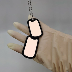 Detail of blank metal dog tags with black borders and silver bead chain on a grey background