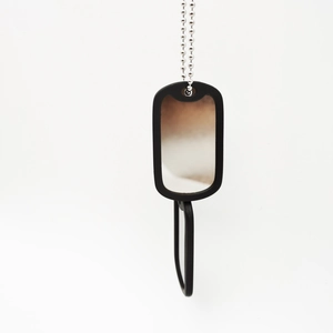 Detail of military style dog tag with black rubber silencer and silver bead chain