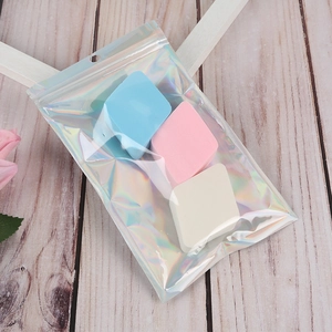 Three polygon makeup sponges in blue, pink, and white inside a holographic resealable bag
