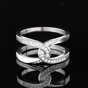 Close-up of silver-plated cross ring with sparkling cubic zirconia on a black surface