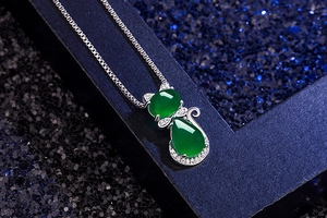 Macro shot of silver cat pendant with green agate stone on a sleek box chain necklace