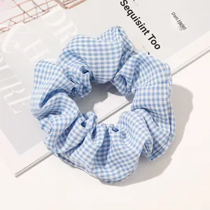 Close-up of blue and white gingham fabric scrunchie on a magazine background