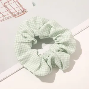 Detailed close-up of a light green checkered fabric scrunchie with soft cotton texture