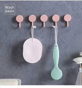 Set of five pink round adhesive wall hooks installed on a grey marble bathroom wall