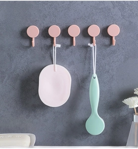 Set of five pink round adhesive wall hooks installed on a grey marble bathroom wall