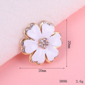 Macro shot of 20mm gold flower brooch with white enamel petals and crystal accents