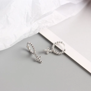 Macro shot of silver geometric bead hoop earrings with cross pendants on soft paper