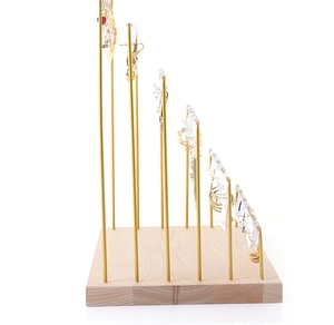 Detail view of multi-tier gold metal earring stand with solid wooden base on white background