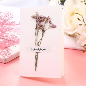 Detail of handmade greeting card featuring purple dried flowers and pink paper