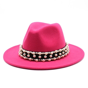 Detail of rose red fedora hat featuring three rows of pearls on black ribbon band
