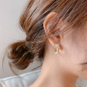 Elegant C-shaped golden earrings with inlaid white pearls for women on model