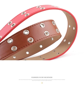 Close-up of red and brown punk belts featuring double silver metal eyelets and texture