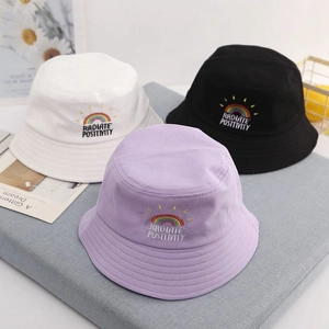 Detail showing rainbow embroidery on cotton bucket hats in white, black, and purple colors