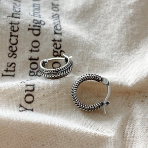 Macro detail of vintage S925 sterling silver stud earrings with woven texture on linen cloth