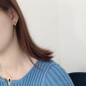 Detail of vintage silver hoop earring and gold necklace with black oval pendant