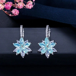 Détail de boucles d'oreilles fleur avec pierres bleues et monture en argent fin