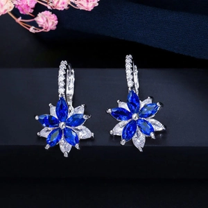 Vue macro de boucles d'oreilles fleur en cristal bleu et blanc sur support noir