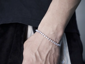 Detail of silver iced-out tennis bracelet with sparkling stones on a male wrist