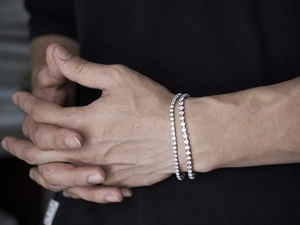 Close-up of dual silver hip hop tennis bracelets with iced out rhinestones on a wrist