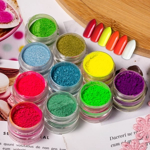 Vue macro de 12 pots de poudre pour ongles et échantillons sur un fond de magazine
