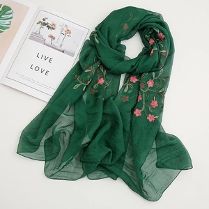 Detail of green chiffon scarf with delicate pink floral embroidery and soft texture