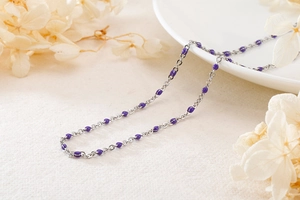 Detail of silver titanium steel chain necklace with purple resin oval beads