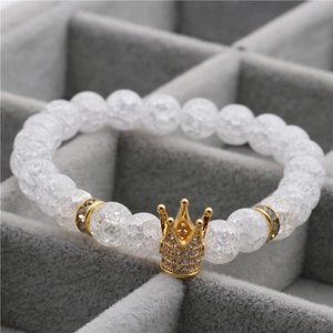 8mm white cracked crystal bead bracelet with a gold crown charm on grey jewelry box