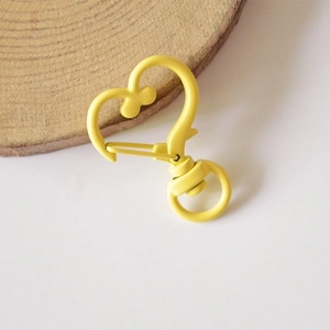 Detail of bright yellow heart-shaped metal carabiner keychain with rotating swivel ring