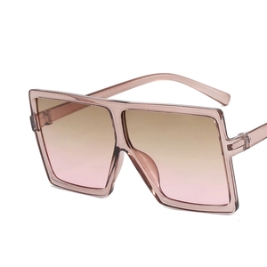Detail view of large square oversized pink sunglasses with gradient lenses on white backdrop