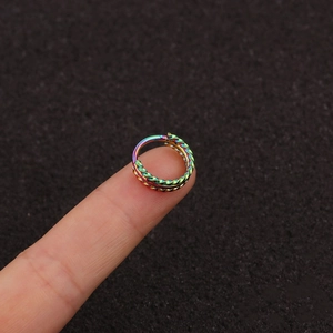 Three-layer braided stainless steel cartilage earring and nose hoop on finger